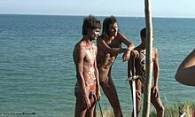 Gostosas tribais de bodypaint posando com espadas e cagando em uma praia